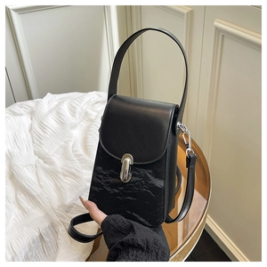 Gros plan d'un sac noir à texture plissée avec une boucle métallique ovale argentée