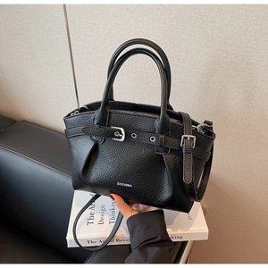 Close-up of black lychee grain leather handbag featuring silver hardware and logo detail