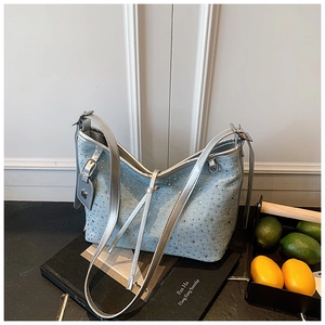 Detail einer hellblauen Denim-Tasche mit silbernen Strasssteinen und Metallriemen