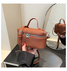 Detail of brown litchi pattern leather bag with top handle and silver hardware zipper