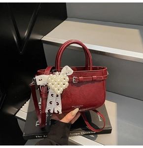 Détail du sac seau en cuir verni bordeaux avec breloque cœur en perle et dentelle