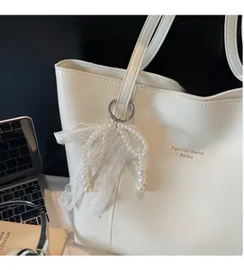 Detail of white PU leather tote bag with elegant lace pearl bow and gold embossed lettering