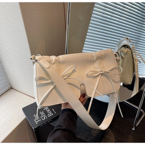 Gros plan détaillé du sac bandoulière crème avec nœud papillon et cuir froissé vintage