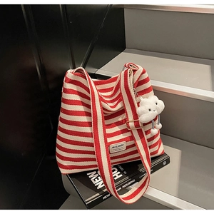 Detail of red striped canvas tote bag with white cloud plush pendant on book