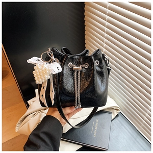 Detail of black pleated bucket bag with lace bow, pearl heart charm and metal chain strap