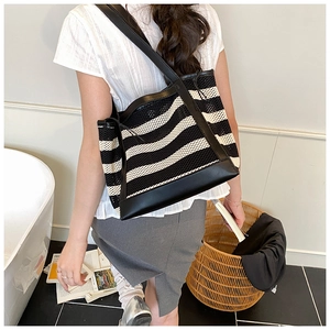 Black and white striped mesh tote bag with leather straps shown from a side-view angle