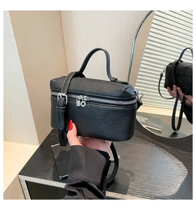 Detail view of black lychee leather box bag with dual zippers and silver lock charms