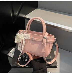 Détail du sac seau rose en cuir PU avec nœud en dentelle et pendentif perle sur escalier