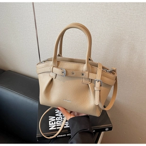 Close-up of pleated khaki lychee grain leather handbag with adjustable shoulder strap