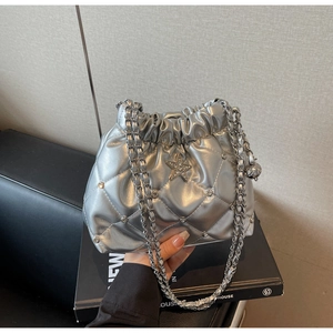 Détail de la pochette argentée matelassée avec emblème en forme d'étoile et strass