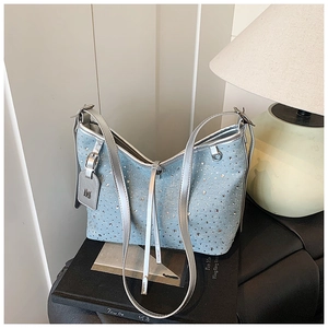Detail der hellblauen Jeans-Beuteltasche mit funkelnden Strasssteinen und silbernem M-Logo