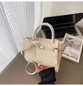 Détail du mini sac seau crème avec breloque cœur en perles et texture cuir ondulé