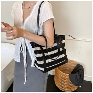 Close-up of black and white striped tote with hollow mesh weave and leather straps