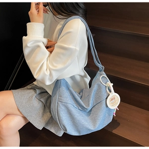 Detail of light blue denim hobo bag featuring a cute capybara pendant and wide strap