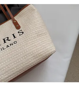 Close-up of rainbow straw tote bag texture with leather handle and black embroidery