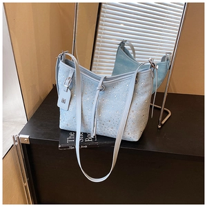 Detail einer hellblauen Jeans-Tasche mit glitzernden Strasssteinen und silbernem M-Anhänger