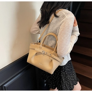 Detail of beige lychee textured handbag with detachable strap and metal buckle hardware