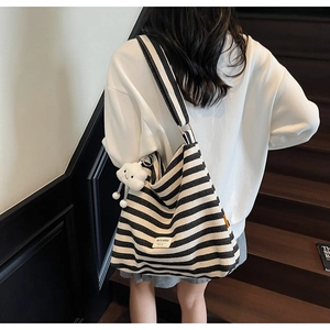 Detail of striped canvas tote bag with wide shoulder strap and white cloud pendant