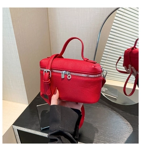 Detail of red lychee pattern leather handbag with silver zipper and buckle accents