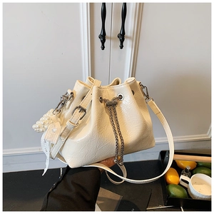 Detail of white glossy drawstring bucket bag with pearl lace charm and chain