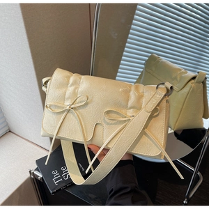 Détail du sac à bandoulière en cuir texturé jaune crème avec nœuds décoratifs chic
