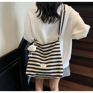 Detail view of large striped canvas tote bag with a plush cloud pendant and logo patch