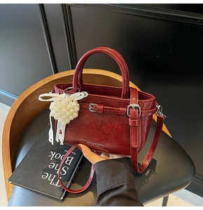 Détail d'un sac seau rouge en similicuir avec breloque cœur perle et nœud en dentelle