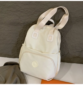 Detail eines beigen Nylon-Rucksacks mit verstärkten Gurten und Mehrfachtaschen-Design