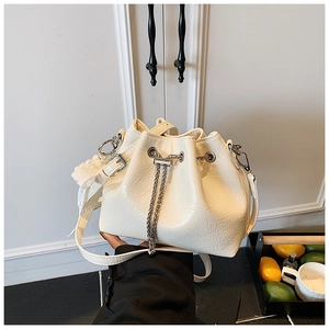 Close-up of cream drawstring bucket bag with pleated texture and pearl charm detail
