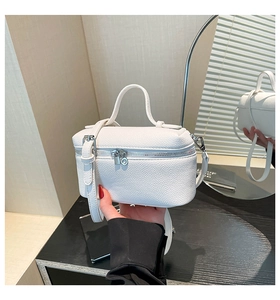 Detail view of white lychee grain leather handbag with silver dual zipper hardware