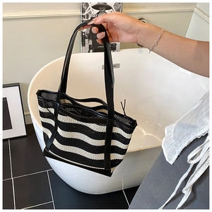 Detail of black and white striped mesh tote bag with reinforced leather trim and handles