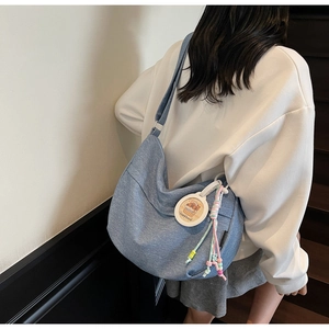 Detail of denim crossbody bag featuring a cartoon capybara charm and colorful beaded tassels
