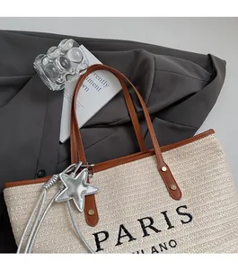 Detailed macro view of woven straw tote bag with leather handles and Paris embroidery