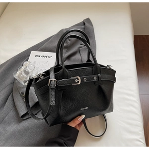 Detail of black lychee grain leather bucket bag with silver buckle on a grey blazer