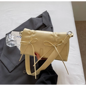 Détail montrant la texture plissée et les deux nœuds sur ce sac à bandoulière crème