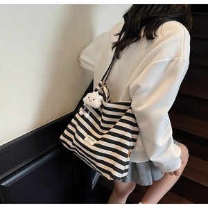 Detail of striped canvas tote bag with MILAIQI label and cute cloud plush charm