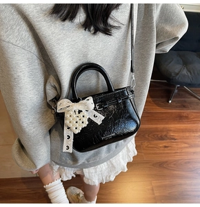Sac bandoulière en cuir verni noir avec nœud en dentelle et breloque perle
