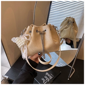 Detail of drawstring bucket bag with pleated leather texture and pearl bow charm