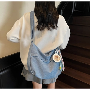 Detail view of denim dumpling bag featuring capybara charm and adjustable crossbody strap