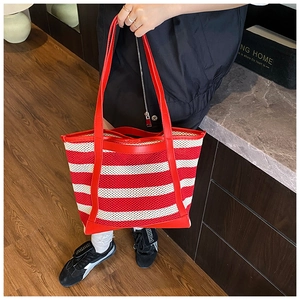 Detail of red and white striped mesh tote bag with smooth leather handles for daily use