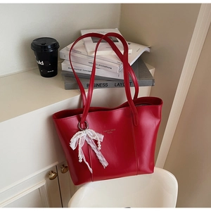 Detail of red PU leather tote bag with pearl lace bow charm and gold logo print