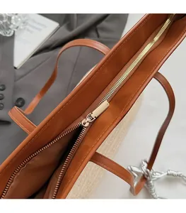 Close-up detail of smooth metal zipper and leather texture on a brown tote bag
