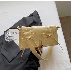 Détail du sac à bandoulière plissé crème avec nœuds et texture en cuir élégante