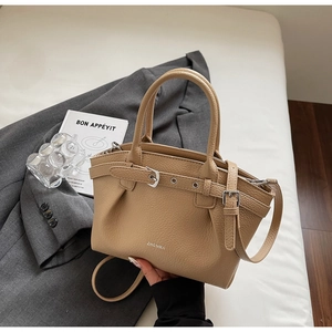Detail of light brown lychee grain leather handbag with silver hardware and brand logo