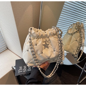 Détail d'un sac seau matelassé avec logo étoile et chaîne se reflétant dans un miroir