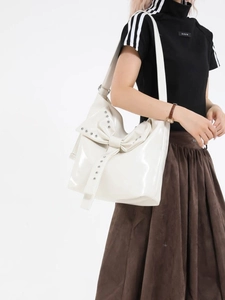 Stylische weiße Shopper-Tasche mit großer Schleife und Nieten am Model im Studio