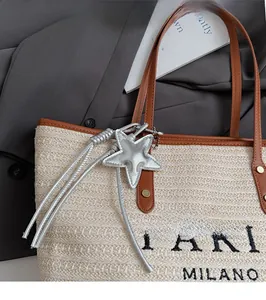Detail of woven straw tote bag with brown leather handles and Paris Milano embroidery