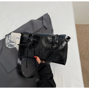 Détails d'un sac à main noir en cuir froissé brillant avec des nœuds décoratifs