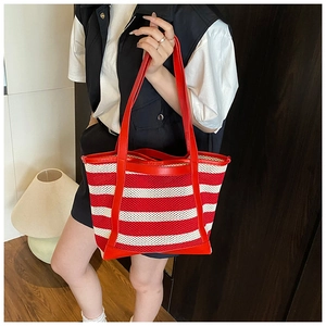 Detail of red and white striped knit tote bag with leather straps on a model