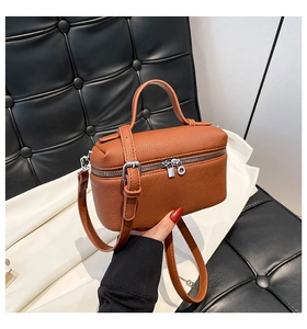 Detail of brown litchi pattern leather handbag with silver zipper and shoulder strap